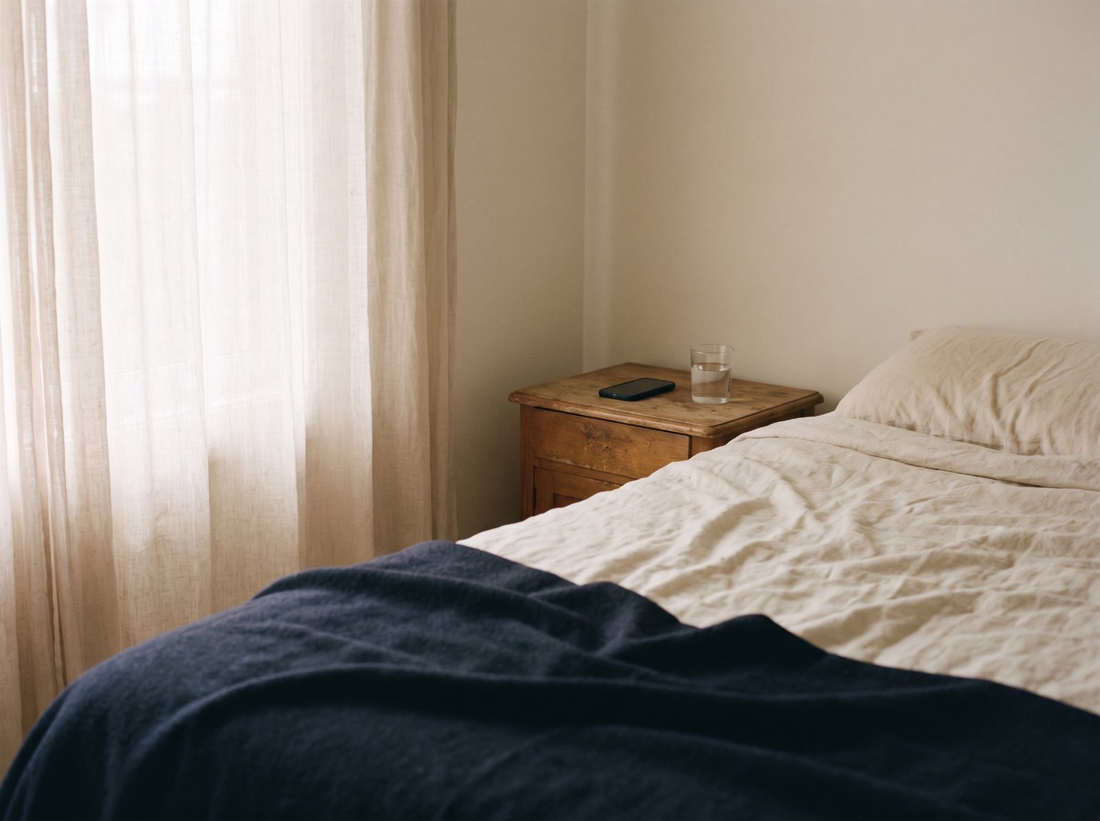 A quiet bedroom in the morning with a phone on the nightstand